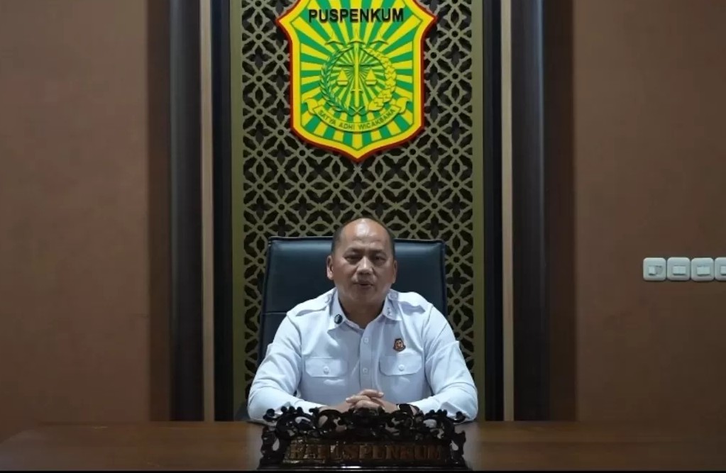 Juru bicara Pusat Penerangan Hukum Kejaksaan RI menyampaikan pernyataan resmi dari ruang konferensi dengan lambang Puspenkum di latar belakang.